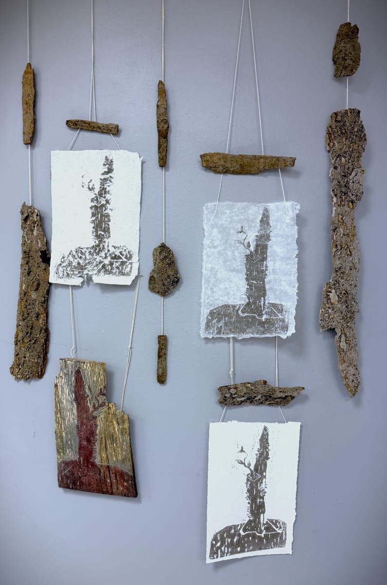 Bark hung on string next to rough paper with a linocut tree artwork printed on it