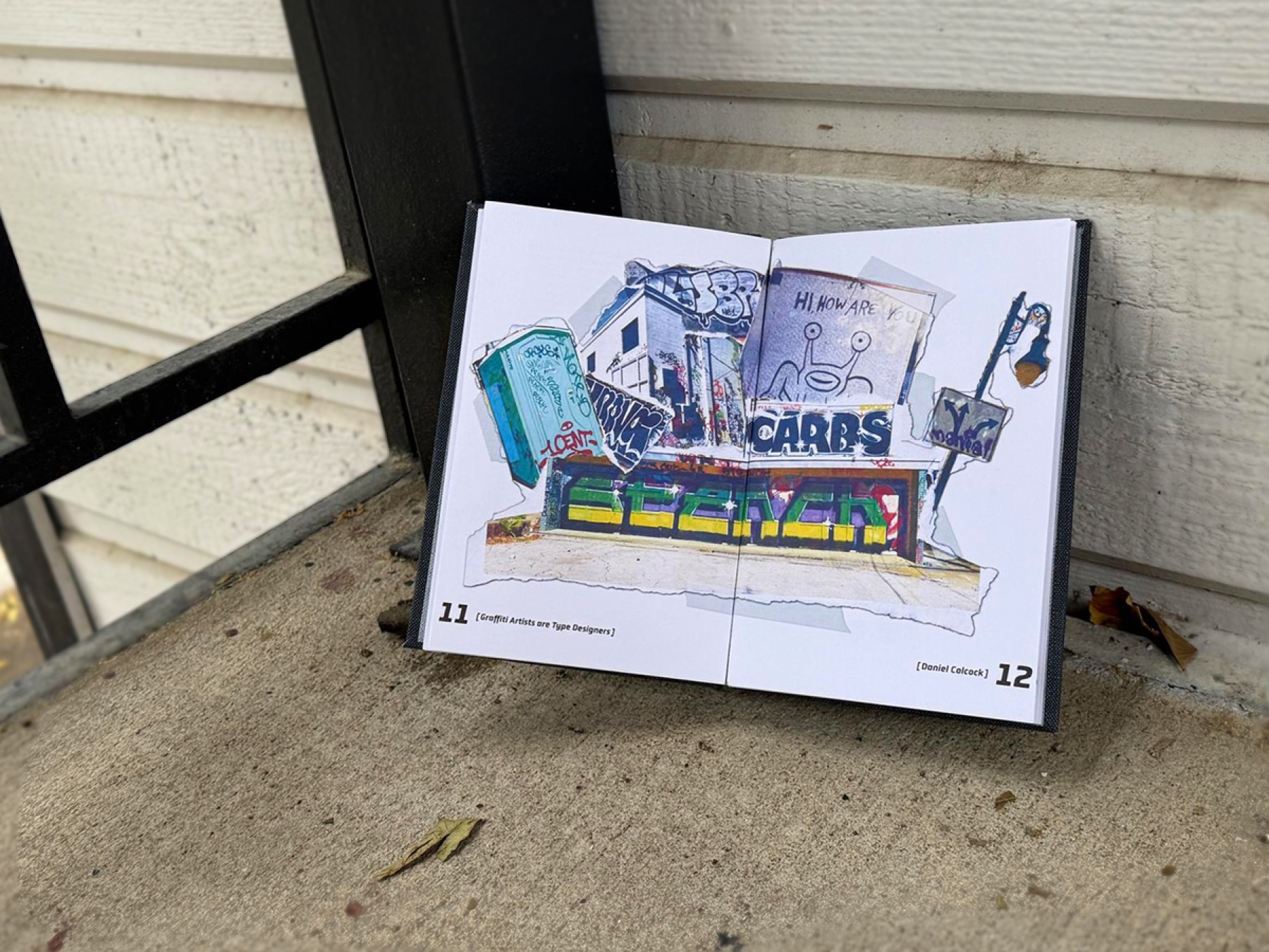 Hand-bound graffiti typography book resting on a concrete curb